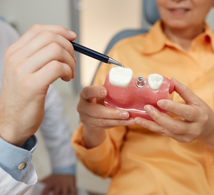 Dentist showing a dental implant model to a patient