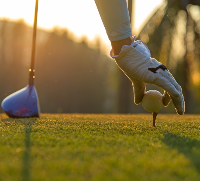 Golf player placing a golf ball on a tee