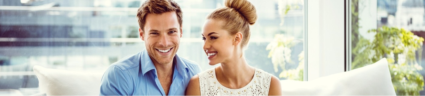 Smiling man and woman sitting on couch together