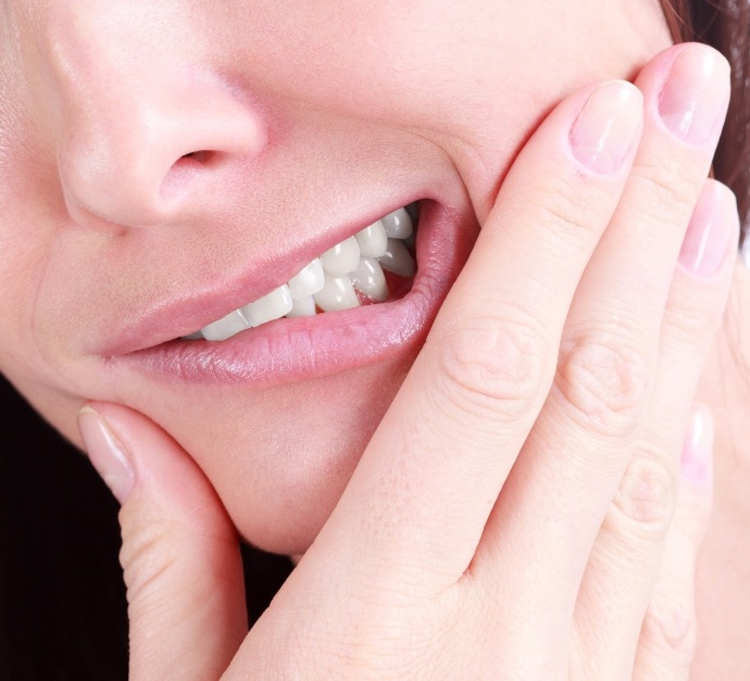 Close up of person wincing and touching their cheek