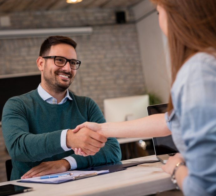 Man and woman shaking hands from across table