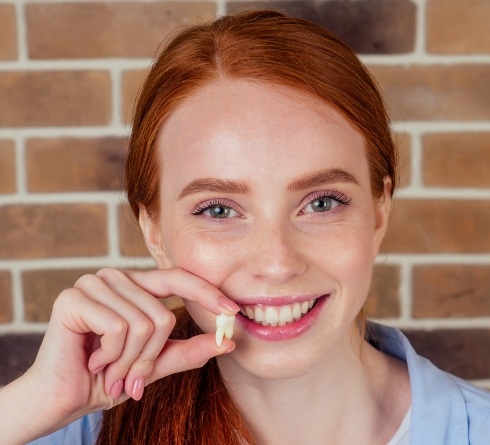 Smiling woman holding an extracted tooth