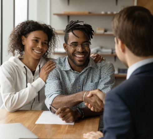 Smiling man shaking hands with person across desk